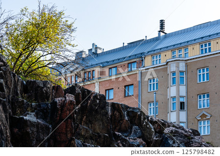 Helsinki's architecture: Apartment buildings rise beyond rocky landscape creating a scenic cityscape. 125798482