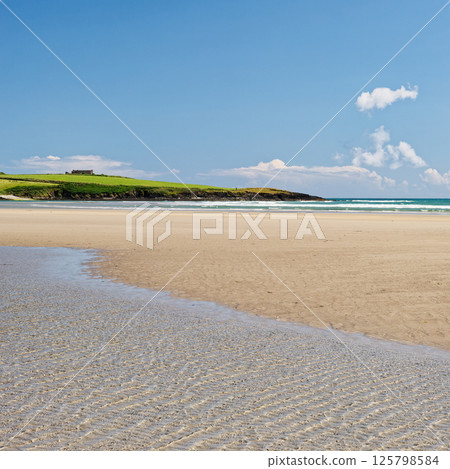 Coastal serenity. A breathtaking view of a tranquil beach on a sunny day, with a vibrant blue sky and gentle waves, perfect for relaxation. Coastal serenity. A breathtaking view of a tranquil beach on a sunny day, with a vibrant blue sky and gentle waves, perfect for relaxation. 125798584