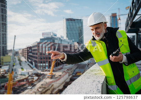 Site manager giving instructions over radio during building inspection. 125798637