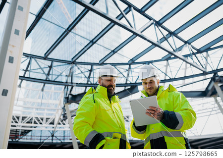 Construction managers using digital tablet on site, reviewing project plans. Construction managers using digital tablet on site, reviewing project plans. 125798665