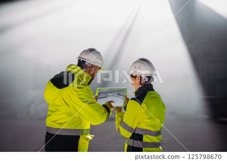 Engineers discussing construction plans using a tablet on site. 125798670