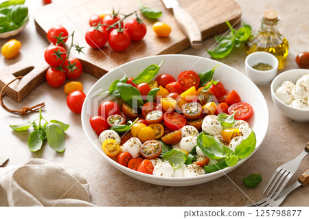 Salad with fresh cherry tomatoes, mozzarella and basil leaves Salad with fresh cherry tomatoes, mozzarella and basil leaves 125798877