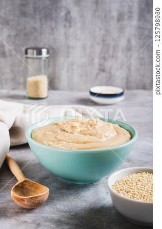 Sesame tahini in a bowl and sesame seeds in a bowl on the table vertical view Sesame tahini in a bowl and sesame seeds in a bowl on the table vertical view 125798980