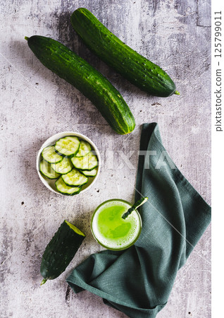 A glass of fresh cucumber juice and cucumbers on the table top and vertical view A glass of fresh cucumber juice and cucumbers on the table top and vertical view 125799011