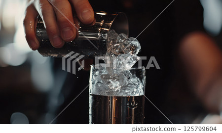 Bartender pouring ice into a glass. Bartender pouring ice into a glass. 125799604
