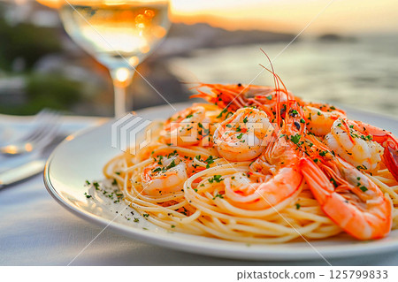 Shrimp pasta is elegantly plated with a view of the sunset over the ocean. 125799833