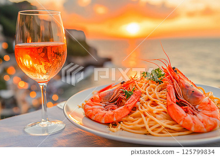 Shrimp pasta is elegantly plated with a view of the sunset over the ocean. 125799834