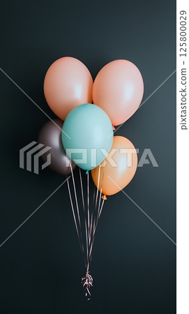 A bunch of colorful party balloons with silver ribbons against a dark gray colored background wall A bunch of colorful party balloons with silver ribbons against a dark gray colored background wall 125800029