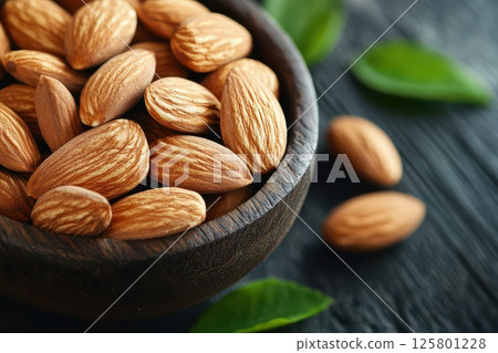 Almonds in wood bowl with leaves Almonds in wood bowl with leaves 125801228