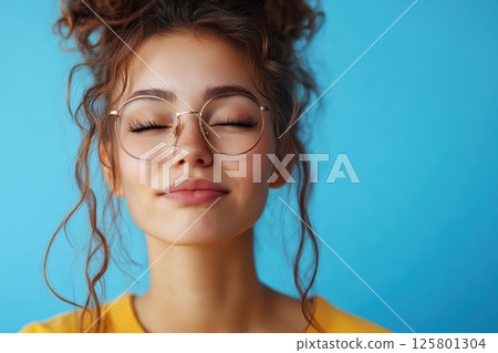 Young woman smiles in front of blue background Young woman smiles in front of blue background 125801304