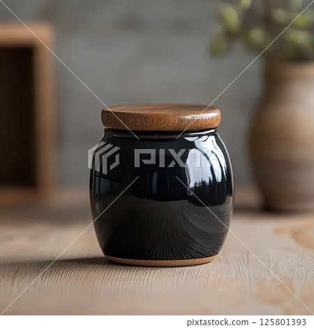 Elegant black jar with wooden lid on rustic table 125801393