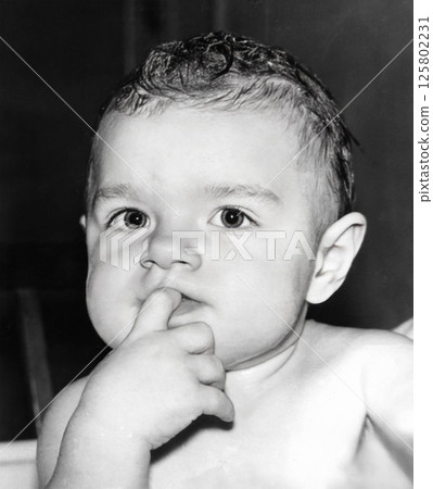 Vintage portrait of a cute little girl with a finger in her mouth. Retro photo from 1994. Vintage portrait of a cute little girl with a finger in her mouth. Retro photo from 1994. 125802231