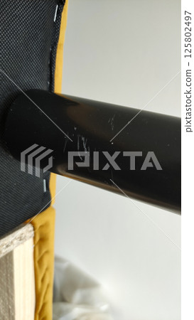 Scratched black metal furniture leg showing wear and tear of sofa Scratched black metal furniture leg showing wear and tear of sofa 125802497