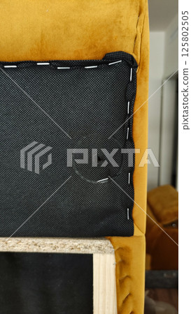 Upholsterer assembling modern furniture with yellow velvet and wooden frame of sofa Upholsterer assembling modern furniture with yellow velvet and wooden frame of sofa 125802505