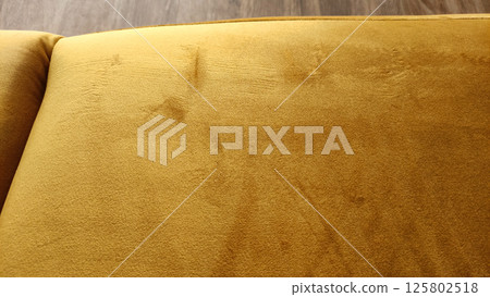 Close up of stained and scratched mustard yellow velvet upholstery of sofa 125802518
