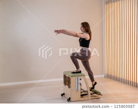 Asian woman doing pilates classic chair.  125803087