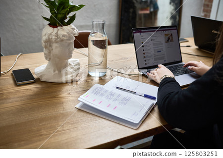 Digital Workspace with Bust Planter, Laptop, Note Taking on Wooden Desk, Inspiring Modern Office Environment Concept Digital Workspace with Bust Planter, Laptop, Note Taking on Wooden Desk, Inspiring Modern Office Environment Concept 125803251