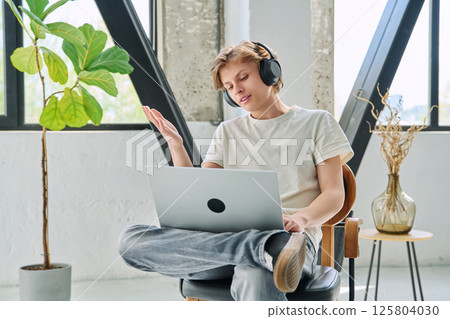 Teenage boy with headphones using laptop for video conference, online meeting 125804030