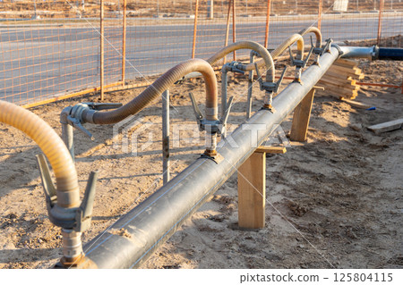 A close-up view of a series of flexible hoses connected to a pipe at a construction site A close-up view of a series of flexible hoses connected to a pipe at a construction site 125804115