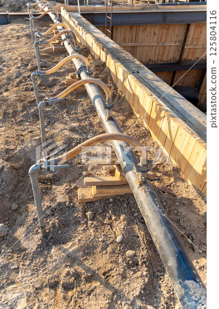 A close-up view of a series of flexible hoses connected to a pipe at a construction site A close-up view of a series of flexible hoses connected to a pipe at a construction site 125804116