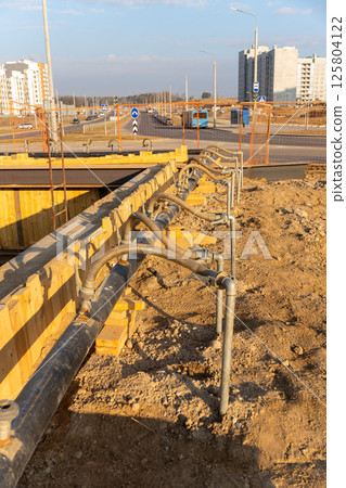A close-up view of a series of flexible hoses connected to a pipe at a construction site 125804122