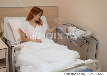 A young mother admires her newborn son in the maternity hospital. A young mother admires her newborn son in the maternity hospital. 125804222