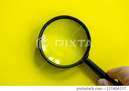 Hand holding a magnifying glass with customizable space for text. 125804237