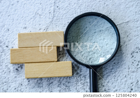 Magnifying glass with customizable space on wooden block for text. 125804240
