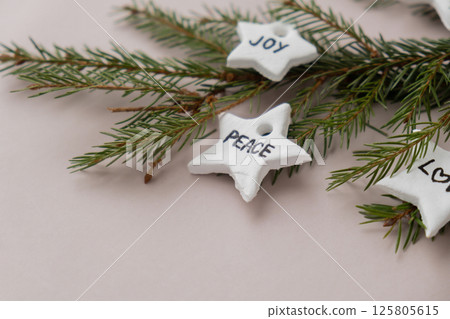 Christmas star with words JOY PEACE LOVE Group of air dry clay handmade Christmas decor on beige background. Children air dry clay activity handicraft idea. Preparing for Christmas holiday decorating 125805615