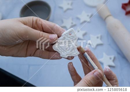 Master class of painting Creator is using white air dry clay for making decor to Christmas tree holiday. Creating hobby recreation activity that involves fingers. DIY crafting Master class of painting Creator is using white air dry clay for making decor to Christmas tree holiday. Creating hobby recreation activity that involves fingers. DIY crafting 125805618