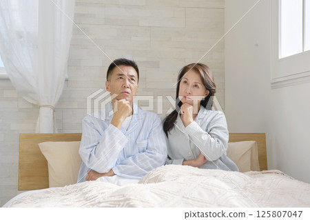 Couple in pajamas thinking Couple in pajamas thinking 125807047