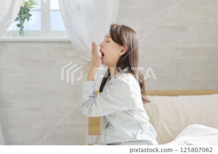 Middle-aged woman in pajamas yawning 125807062