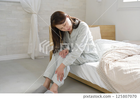 Middle-aged woman in pajamas with sore feet Middle-aged woman in pajamas with sore feet 125807070