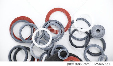 An overhead shot of diverse rubber gaskets in varying sizes and hues on a white background. An overhead shot of diverse rubber gaskets in varying sizes and hues on a white background. 125807857