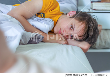 Teenager wakes up, lies in bed and looks calm, thoughtful and sad 125808057