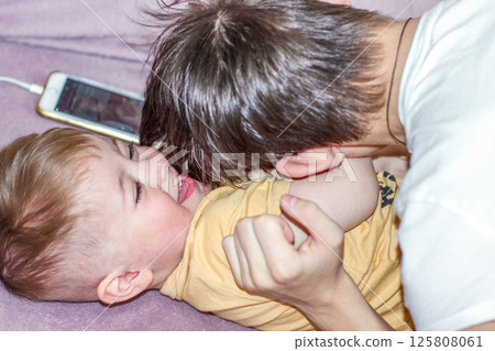 Teenage boy happily playing with his younger brother while looking after him 125808061