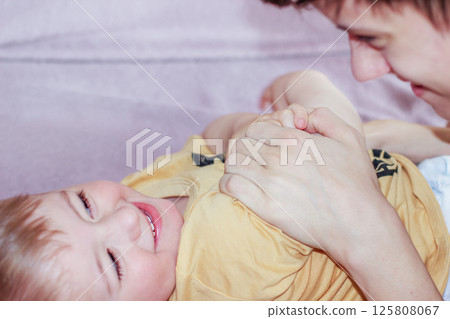 Teenage boy happily playing with his younger brother while looking after him 125808067