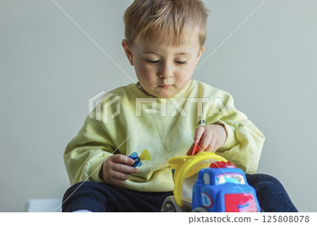 Little boy playing with toy car, child developing 125808078