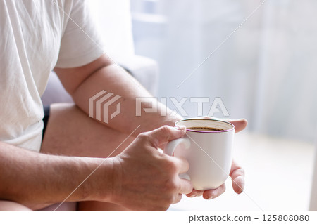 Man drinking morning coffee, white cup of coffee in man's hands Man drinking morning coffee, white cup of coffee in man's hands 125808080