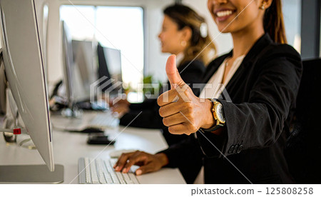 businesswoman giving thumbs up in office setting, expressing approval and positivity while working on computer. atmosphere is professional and collaborative businesswoman giving thumbs up in office setting, expressing approval and positivity while working on computer. atmosphere is professional and collaborative 125808258