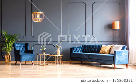 Luxurious blue velvet sofa and armchair in modern living room with dark blue walls, stylish gold accents, and elegant decor. space exudes sophistication and comfort 125808351
