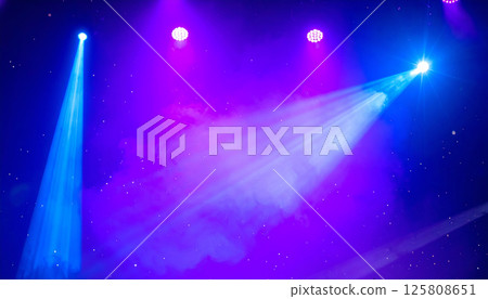Colorful stage lights in purple and blue cast beams through starry background, creating vibrant and dynamic atmosphere that captivates audience attention Colorful stage lights in purple and blue cast beams through starry background, creating vibrant and dynamic atmosphere that captivates audience attention 125808651