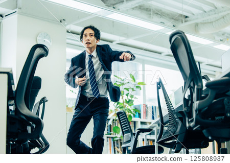 A businessman in a suit running in the office 125808987