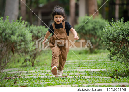 happy toddler girl walking on stone pathway in garden 125809196