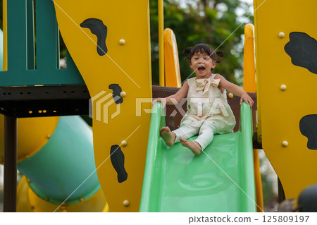 happy toddler baby girl sliding and playing at playground 125809197