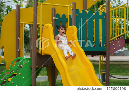 happy toddler baby girl sliding and playing at playground 125809198