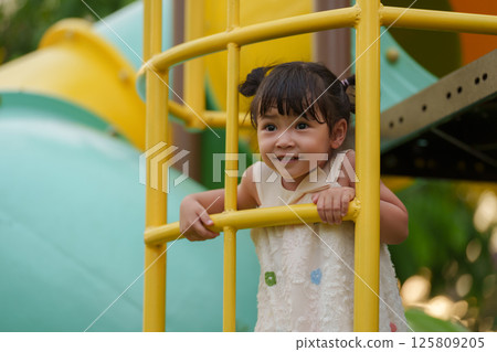 happy toddler girl playing and climbing on outdoor playground at park happy toddler girl playing and climbing on outdoor playground at park 125809205
