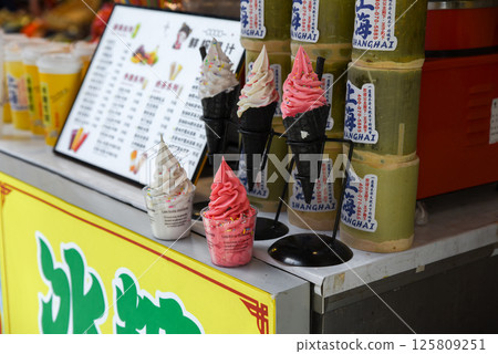 Shanghai, China - 1 April 2025: Colorful soft serve ice cream in black cones and cups on display at a street food stall on Yuyuan Old Street in Shanghai 125809251
