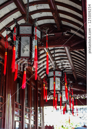 Shanghai, China - 1 April 2025: Traditional Chinese lanterns with red tassels hanging under a curved wooden roof in Yu Garden, a famous historical site in Shanghai Shanghai, China - 1 April 2025: Traditional Chinese lanterns with red tassels hanging under a curved wooden roof in Yu Garden, a famous historical site in Shanghai 125809254