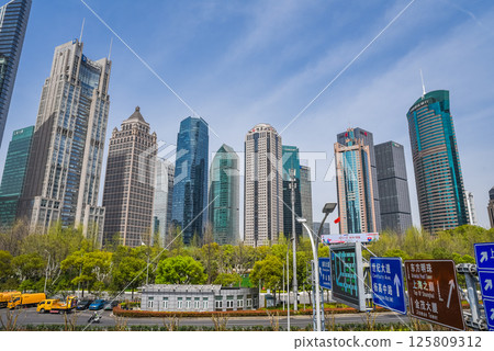 Shanghai, China - 1 April 2025: Modern Pudong district skyline showcasing diverse architectural styles - glass towers, classical and futuristic buildings, framed by spring foliage in foreground park. Shanghai, China - 1 April 2025: Modern Pudong district skyline showcasing diverse architectural styles - glass towers, classical and futuristic buildings, framed by spring foliage in foreground park. 125809312